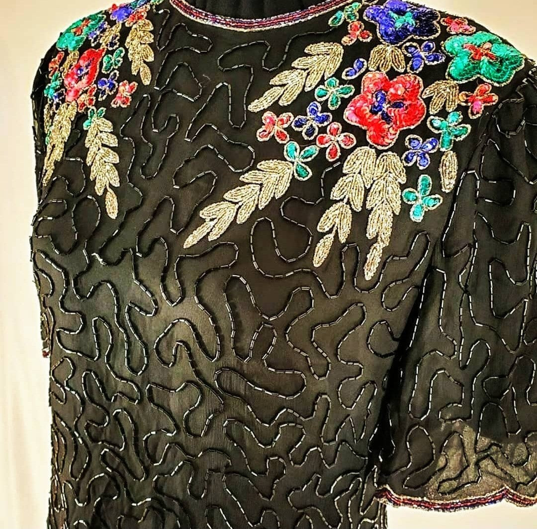 close up front view of 80s top with flower adorned beaded top on mannequin